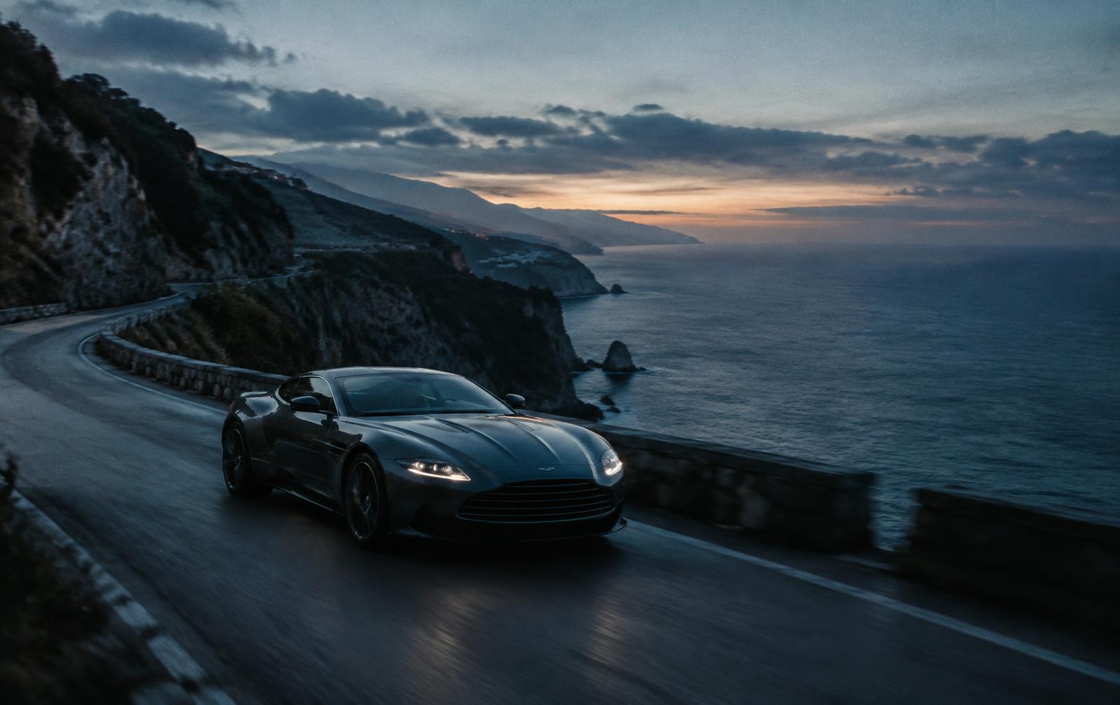 A grand tourer on a coastal cliff road at dawn